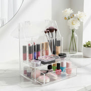 Clear acrylic makeup organizer with various cosmetic items on a white surface.