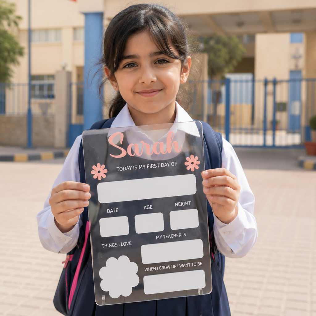 Custom personalized acrylic First Day of School sign board held by a young Kuwaiti schoolgirl in front of a school in Kuwait.
العربية: لوحة أكريليك مخصصة لليوم الأول من المدرسة تحمل اسم الطفل، تمسك بها طالبة كويتية صغيرة أمام مدرسة في الكويت.
